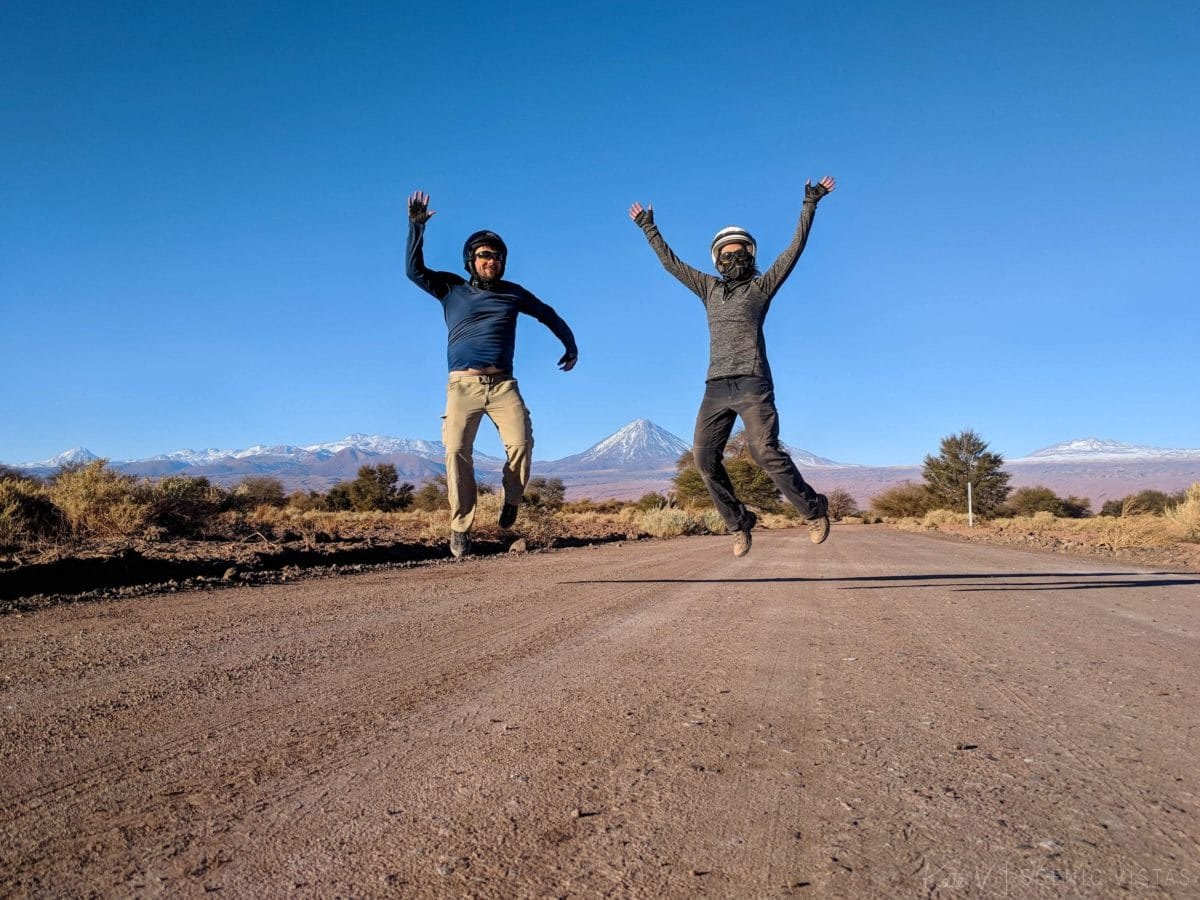 Jumping tourist photo of a couple on a dirt road in the Atacama Desert.