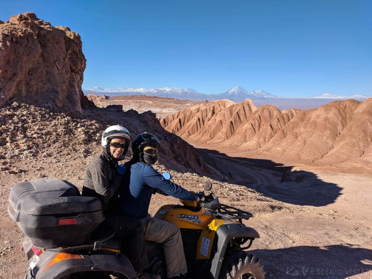 Couple riding an ATV in front of the lunar landscape of the Cordillera de la Sal.